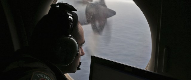 Flight officer Rayan Gharazeddine, on board a Royal Australian Air Force AP-3C Orion, scans for missing Malaysia Airlines flight MH370 in the southern Indian Ocean on March 22, 2014. The Orion under took a four-hour journey to search an area approximately 2,500 kms southwest of Perth, two hours on station searching at about 400 feet above the ocean, and then a four-hour return. China released on March 22 a new satellite image of a large floating object possibly linked to missing Malaysia Airlines flight MH370, boosting search efforts as anger with the pace of the operation boiled over among Chinese relatives in Beijing. AFP PHOTO / POOL / Rob Griffith (Photo credit should read ROB GRIFFITH/AFP/Getty Images)
