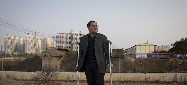 In this Monday, Jan. 20, 2014 photo, Zhou Wangyan, head of the Liling city land resources bureau, stands with crutches near a plot of land under development in Liling city in central China's Hunan province. Zhou said he was detained by anti-corruption investigators for 184 days, deprived of sleep and food, nearly drowned, whipped with wire, forced to eat excrement, and that interrogators broke his left leg. "It was a living hell," he said. "It was worse than being a pig or a dog." Local anti-graft officials on a Hunan online forum in February 2012 denied Zhou was tortured, saying he injured himself by slipping in the bathroom. (AP Photo/Andy Wong)