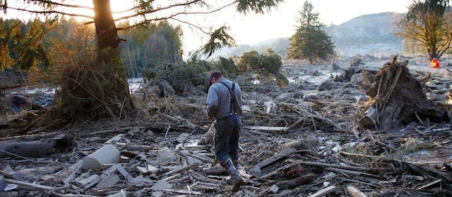 Steve Skaglund walks across the rubble on the east side of Saturday's fatal mudslide near Oso, Wash., Sunday, March 23, 2014. (AP Photo /The Herald, Genna Martin)