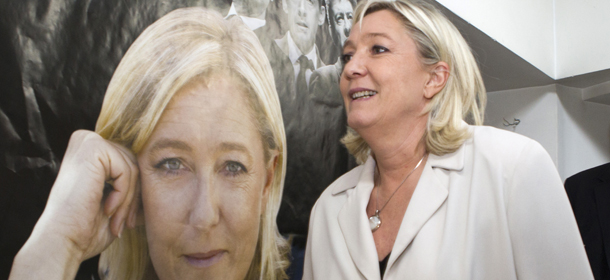 FILE - - In this March 8, 2014 file photo, French far-right party leader Marine Le Pen walks past a poster of her at the party headquarters in Henin-Beaumont, northern France, as part of the municipal campaign. Marine Le Pen sees political gold in the abandoned coal mines of northern France that once pumped life, jobs and an identity into places like Henin-Beaumont, a bleak town that the far-right leader says is the avant-garde of her anti-immigration party's march to power. (AP Photo/Jacques Brinon, File)