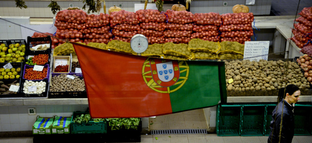 A customer passes by under a Portuguese flag at the Saldanha traditional market in downtown Lisbon on January 15, 2014. AFP PHOTO/ PATRICIA DE MELO MOREIRA (Photo credit should read PATRICIA DE MELO MOREIRA/AFP/Getty Images)