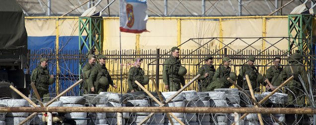 Soldiers in unmarked uniforms walk near Ukrainian marine base in the city of Feodosia, Crimea, Sunday, March 23, 2014. On Sunday, the Russian Defense Ministry said the Russian flag was now flying over 189 military facilities in Crimea. It didn't specify whether any Ukrainian military operations there remained under Ukrainian control. (AP Photo/ Pavel Golovkin)
