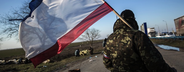 A pro-Russia supporter waves a Crimean flag at Chongar checkpoint blocking the entrance to Crimea on March 10, 2014. Russia vowed on March 10 to unveil its own solution to the Ukrainian crisis that would run counter to US efforts and would appear to leave room for Crimea to switch over to Kremlin rule. The unexpected announcement came as Ukraine's new pro-European leaders raced to rally Western support in the face of the seizure by Kremlin-backed forces of the strategic Black Sea peninsula and plans to hold a Sunday referendum on switching Crimea's allegiance from Kiev to Moscow. AFP PHOTO/ ALISA BOROVIKOVA (Photo credit should read ALISA BOROVIKOVA/AFP/Getty Images)