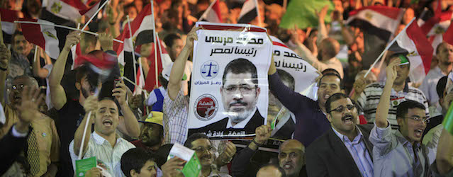 FILE - In this Monday, April 30, 2012 file photo, Egyptian supporters of Mohammed Morsi, Muslim Brotherhood's presidential candidate, wave posters of him with Arabic that reads, "Mohammed Morsi for Egyptian presidency," during a campaigning conference in Cairo Egypt. On the campaign trail for the presidential election, now only nine days away, the Muslim Brotherhood has taken a sharp turn rightward, becoming bolder in saying it wants to bring a state where religiosity and Islamic law play a major role and insisting that it has the right to rule. (AP Photo/Amr Nabil, File)