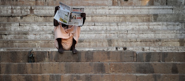 This picture shows a man reading a newspaper by the Ganges river on April 26, 2012 in Varanasi. AFP PHOTO / GABRIEL BOUYS (Photo credit should read GABRIEL BOUYS/AFP/GettyImages)