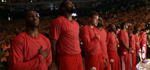 Members of the Los Angeles Clippers listen to the national anthem before Game 4 of an opening-round NBA basketball playoff series against the Golden State Warriors on Sunday, April 27, 2014, in Oakland, Calif. The Clippers chose not to speak publicly about owner Donald Sterling. Instead, they made a silent protest. The players wore their red Clippers' warmup shirts inside out to hide the team's logo. (AP Photo/Marcio Jose Sanchez)