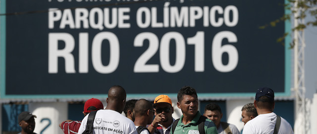 Striking workers stand in front the entrance of the Olympic Park, the main cluster of venues under construction for the 2016 Summer Olympic Games, in Rio de Janeiro, Brazil, Tuesday, April 8, 2014. The labor dispute centers around which union represents the construction workers, and also involves benefits and working conditions. (AP Photo/Silvia Izquierdo)