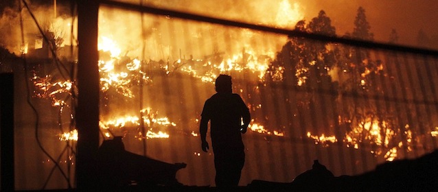 A man walks as an out of control forest fire destroys homes in the city of Valparaiso, Chile, Sunday April 13, 2014. Firefighters struggled for a second night to contain blazes that reached this port city, killing at least a dozen people, destroyed hundreds homes and has forced the evacuation of thousands. (AP Photo/Luis Hidalgo)
