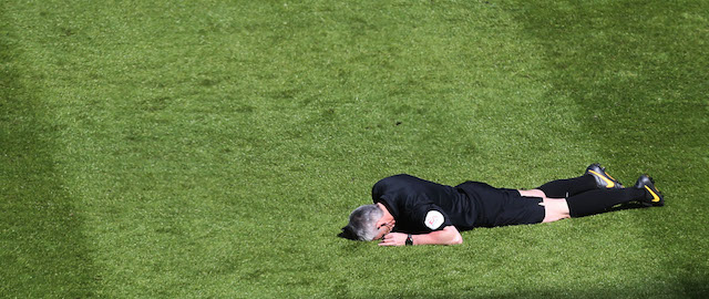 Referee Chris Foy, center, is laid on the pitch after being struck by a ball to the face during the English Premier League soccer match between Newcastle United and Swansea City at St James' Park, Newcastle, England, Saturday, April 19, 2014. (AP Photo/Scott Heppell)