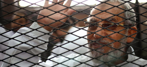 Egyptian Muslim Brotherhood's supreme guide , Mohamed Badie waves from inside the defendants cage during the trial of Brotherhood members on February 3, 2014 in the police institute near Cairo's Turah prison. The trial resumes of Mohamed Badie and more than 50 others on charges of inciting violence that left two dead in the Nile Delta city of Qaliub, after the ouster of Islamist president Mohamed Morsi. AFP PHOTO / AHMED GAMIL (Photo credit should read AHMED GAMIL/AFP/Getty Images)