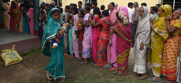 An Indian voter, seen carrying her child, walks past other voters waiting in line outside a polling stating after casting her vote in Dibrugarh on April 7, 2014, during national elections. Indians have begun voting in the world's biggest election which is set to sweep the Hindu nationalist opposition to power at a time of low growth, anger about corruption and warnings about religious unrest. India's 814-million-strong electorate are forecast to inflict a heavy defeat on the ruling Congress party, in power for 10 years and led by India's famous Gandhi dynasty. AFP PHOTO/Dibyangshu SARKAR (Photo credit should read DIBYANGSHU SARKAR/AFP/Getty Images)