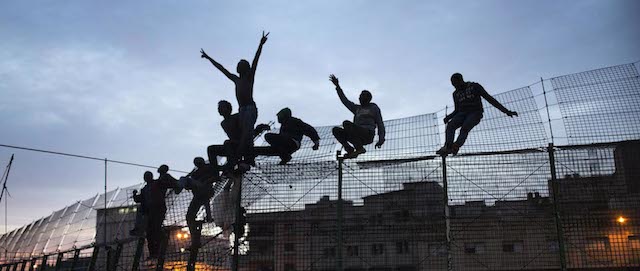 Migranti oltrpassano la recinzione che divide il Marocco da Melilla, 28 marzo 2014. 
(AP Photo/Santi Palacios)