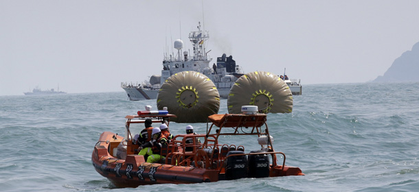 South Korean Coast Guard police officers on a boat sail to rescue missing passengers believed to have been trapped in the sunken ferry Sewol near the buoys which were installed to mark the vessel in the water off the southern coast near Jindo, south of Seoul, South Korea, Sunday, April 20, 2014. After more than three days of frustration and failure, divers on Sunday finally found a way into the submerged ferry off South Korea's southern shore, discovering more than a dozen bodies inside the ship and pushing the confirmed death toll to over four dozen, officials said. (AP Photo/Lee Jin-man)