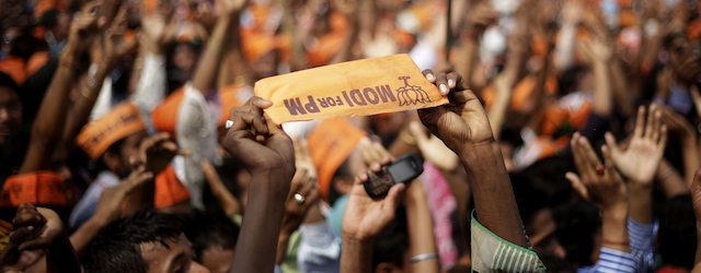 A supporter of India's main opposition Bharatiya Janata Party (BJP) holds a banner, upside down, in support of prime ministerial candidate Narendra Modi during an election campaign rally in Nagaon, in the northeastern Indian state of Assam, Saturday, April 19, 2014. As India, Asia's third-largest economy, holds elections that will gauge the mood of millions of new voters, Modi's Hindu nationalist party is proclaiming the economic success of Gujarat, the western state he's led for more than decade. Critics, however, question whether the extra wealth has translated into better lives for the state’s 60 million people. (AP Photo/Anupam Nath)