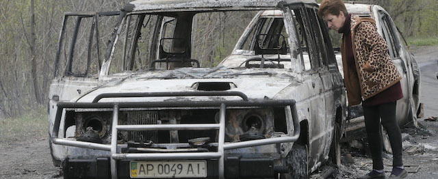 A local resident inspects burnt-out cars after night fight at the checkpoint which under control of pro-Russian activists in the village of Bulbasika near Slovyansk on Sunday, April 20, 2014. Pro-Russian insurgents defiantly refused to surrender their weapons or give up government buildings in eastern Ukraine, despite a diplomatic accord reached in Geneva and overtures from the government in Kiev. (AP Photo/Efrem Lukatsky)