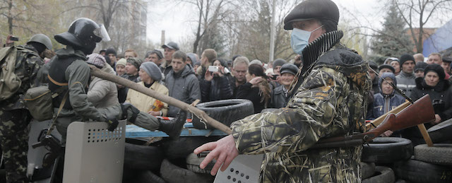 Armed pro-Russian activists occupy the police station carrying riot shields as people watch on, in the eastern Ukraine town of Slovyansk on Saturday, April 12, 2014. Pro-Moscow protesters have seized a number of government buildings in the east over the past week, undermining the authority of the interim government in the capital, Kiev. (AP Photo/Efrem Lukatsky)