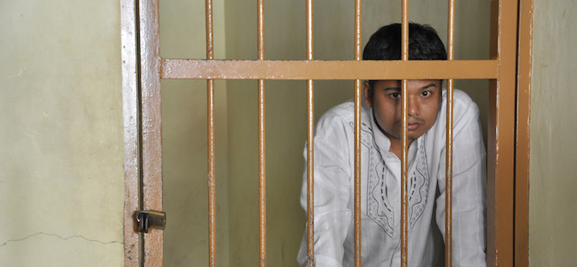 Thirty year old Indonesian, Alexander Aan waits in the jail holding area during his verdict at the Muaro Sijunjung district court in West Sumatra on June 14, 2012. Aan, writing "God doesn't exist" on his Facebook page, was jailed for 30 months for sharing explicit material about the Prophet Mohammed online. The court found Aan guilty of "deliberately spreading information inciting religious hatred and animosity." AFP PHOTO (Photo credit should read STR/AFP/GettyImages)