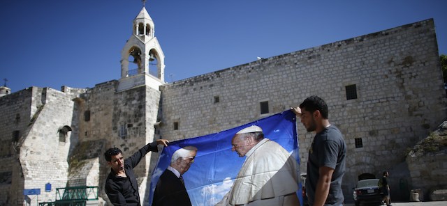 Palestinian workers hold a banner bearing portraits of Palestinian Authority president Mahmud Abbas (L) and Pope Francis in front of the Church of Nativity, in the West Bank Town of Bethlehem, on May 14, 2014. The pope's visit is scheduled to begin in Jordan on May 24, and he is then due to spend two days in the Holy Land from May 25. AFP PHOTO / THOMAS COEX (Photo credit should read THOMAS COEX/AFP/Getty Images)