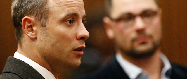 Oscar Pistorius, listens as a court ruling is handed down that he would undergo psychiatric evaluation in Pretoria, South Africa, Tuesday, May 20, 2014. Pistorius is charged with the shooting death of his girlfriend Reeva Steenkamp on Valentine's Day in 2013. At back right is brother Carl Pistroius. (AP Photo/Siphiwe Sibeko, Pool)