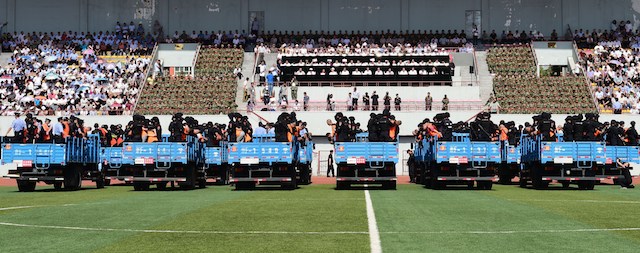 This picture taken on May 27, 2014 shows security forces standing behing the accused wearing orange vests on trucks during a mass sentencing in Ili prefecture, northwest China's Xinjiang region. Authorities in China's mainly Muslim Xinjiang mounted a mass sentencing in a stadium for 55 people on offences including terrorism, state media said on May 28, as they press a crackdown on escalating violence. CHINA OUT AFP PHOTO (Photo credit should read AFP/AFP/Getty Images)
