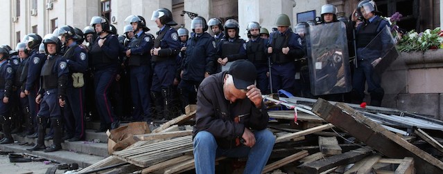 A Pro-Russian activist sits in front of policemen guarding the burned trade union building in the southern Ukrainian city of Odessa on May 3, 2014. More than 30 people were killed in a "criminal" blaze in Ukraine's southern city of Odessa, as violence spread across the country during the bloodiest day since Kiev's Western-backed government took power. Ukraine's interior ministry said at least 31 people had died in the fire Friday, with local media reporting that pro-Russian militants were believed to have been in the burning building at the time. AFP PHOTO/ ANATOLII STEPANOV (Photo credit should read ANATOLII STEPANOV/AFP/Getty Images)