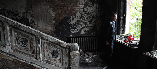 A man lays flowers inside the burnt trade union building in Odessa, Ukraine, Sunday, May 4, 2014. More than 40 people died in the riots, which some from gunshot wounds, but most in a horrific fire that tore through the trade union building late Friday. (AP Photo/Sergei Poliakov)