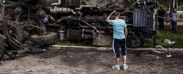 A Ukrainian man stands in front of a destroyed truck, which was previously used by pro-Russian militants and which was bombed by Ukrainian army soldiers overnight during clashes, in the eastern Ukrainian city of Donetsk, on May 27, 2014. Ukraine said today it had regained control of the airport in the eastern city of Donetsk after a day of punishing air strikes and fierce fighting with pro-Moscow separatist gunmen left dozens of people dead. AFP PHOTO / FABIO BUCCIARELLI