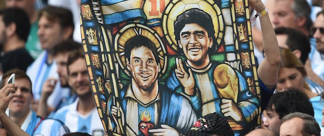 An Argentina's fan holds an image of Argentina's forward Lionel Messi and former footballer Diego Maradona as Saints, before for the Group F football match between Nigeria and Argentina at the Beira-Rio Stadium in Porto Alegre during the 2014 FIFA World Cup on June 25, 2014. AFP PHOTO / PEDRO UGARTE