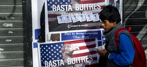 A young man passes by posters on a wall against the "vulture funds" in Buenos Aires on June 18, 2014. The US Supreme Court Monday rejected Argentina's appeals against paying at least $1.3 billion to hedge fund investors in its defaulted bonds, piling pressure on the country's finances. Economy Minister Axel Kicillof warned Tuesday that if Argentina implements a new US court ruling against Buenos Aires, it would push the South American nation into default. The posters read "Enough Vultures - Argentine united in a national cause" AFP PHOTO/ALEJANDRO PAGNI (Photo credit should read ALEJANDRO PAGNI/AFP/Getty Images)