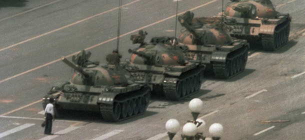 In this combination of photos, a file photo taken June 5, 1989, top, shows a lone Chinese man standing to block a line of tanks heading east on Beijing's Changan Blvd. near Tiananmen Square, and in a May 27, 2014 photo of the same spot, bottom, almost 25 years later, a convoy of cars drive across Beijing's Changan Blvd. near Tiananmen Square. A quarter century after the Communist Partyís attack on demonstrations centered on Tiananmen Square on June 4, 1989, the ruling party prohibits public discussion and 1989 is banned from textbooks and Chinese websites. (AP Photo/Jeff Widener, top, Helene Franchineau, bottom)