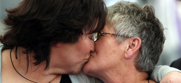 Lynley Bendall (L) and Ally Wanikau kiss one another upon their arrival in Auckland on August 19, 2013 after making history celebrating the legalisation of same-sex marriage in New Zealand by saying I do in the skies on a flight from Queenstown to Auckland. Dozens of same-sex couples said "I do" as New Zealand became the first Asia-Pacific country, and only the 14th in the world, to legalise gay marriage. Vows were exchanged in venues ranging from an airliner cruising at 30,000 feet (9,150 metres) to a historic bath house as gay men and women took advantage of the law change. AFP PHOTO / Michael BRADLEY (Photo credit should read MICHAEL BRADLEY/AFP/Getty Images)