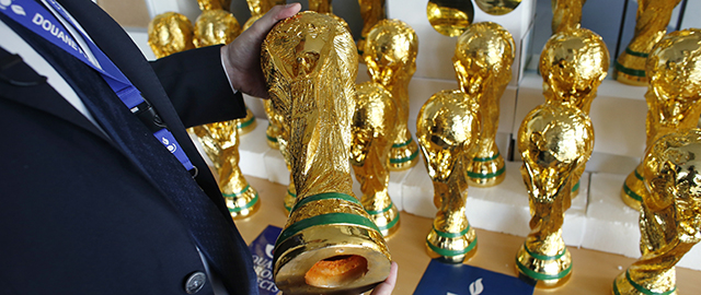 A French customs officer holds a fake football World Cup trophy, in Roissy-en-France on June 25, 2014. France's authorities seized thirty replicas of the FIFA World Cup from China at the Roissy-Charles-de-Gaulle airport, outside Paris. AFP PHOTO / THOMAS SAMSON