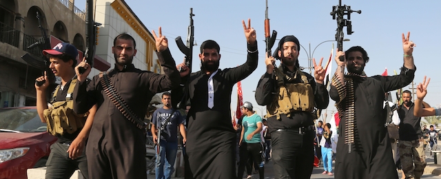 Shiite tribal fighters raise their weapons and chant slogans against the al-Qaida-inspired Islamic State of Iraq and the Levant (ISIL) in the northwest Baghdad's Shula neighborhood, Iraq, Monday, June 16, 2014. Sunni militants captured a key northern Iraqi town along the highway to Syria early on Monday, compounding the woes of Iraq's Shiite-led government a week after it lost a vast swath of territory to the insurgents in the country's north. (AP Photo/ Karim Kadim)