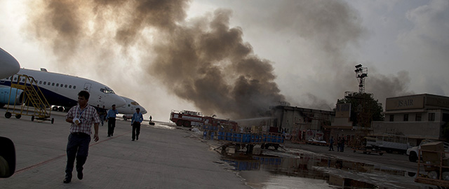Smoke rises above the Jinnah International Airport where security forces battled militants Monday, June 9, 2014, in Karachi, Pakistan. Gunmen disguised as police guards attacked a terminal with machine guns and a rocket launcher during a five-hour siege that killed at least 18 people as explosions echoed into the night, while security forces retaliated and killed all the attackers, officials said Monday. (AP Photo/Shakil Adil)