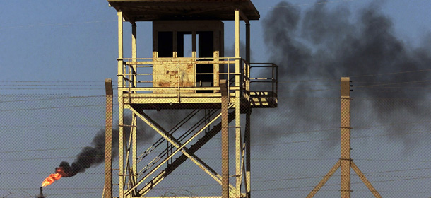 File - In this Monday, Oct. 6, 2003 file photo, an abandoned watchtower and lines of barbed wire are seen surrounding Iraq's largest oil refinery as smoke rises from a petroleum gas flare, in the city of Beiji, north of Baghdad. On Wednesday, June 18, 2014, a top Iraqi security official said Islamic militants of the al-Qaida-inspired Islamic State of Iraq and the Levant laid siege to Iraq's largest oil refinery late Tuesday night, threatening a facility key to the country's domestic supplies as part of their ongoing lightning offensive across the country. The Beiji refinery accounts for a little more than a quarter of the country's entire refining capacity and any lengthy outage at Beiji risks long lines at the gas pump and electricity shortages, adding to the chaos already facing Iraq. (AP Photo/Ivan Sekretarev, File)