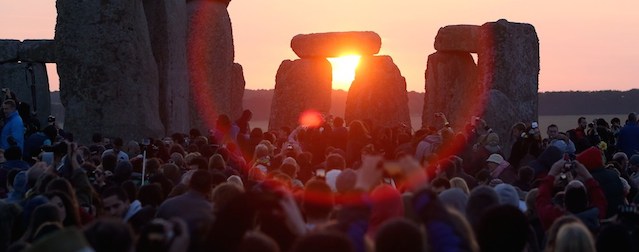 Revelers watch as the sun rises over the standing stones at the prehistoric monument Stonehenge, near Amesbury in Southern England, on June 21, 2014, as revelers gather to celebrate the 2014 summer solstice, marking the longest day of the year. The festival, which dates back thousands of years, celebrates the longest day of the year when the sun is at its maximum elevation. Modern druids and people gather at the landmark Stonehenge every year to see the sun rise on the first morning of summer. AFP PHOTO / GEOFF CADDICK (Photo credit should read GEOFF CADDICK/AFP/Getty Images)
