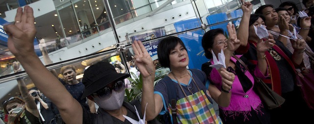 Protester wear a mask raise three fingers represent liberty, brotherhood and equality while protesting during an anti-coup demonstration in Bangkok, Thailand Sunday, June 1, 2014. Hundreds of demonstrators shouting "Freedom!" and "Democracy!" gathered Sunday near a major shopping mall in downtown Bangkok to denounce the country's May 22 coup despite a lockdown by soldiers of some of the city's major intersections.(AP Photo/Sakchai Lalit)