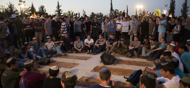 MODI'IN, ISRAEL - JULY 01: People mourn by the graves during the funeral ceremony held for the three Israeli teenagers found dead, on July 1, 2014 in Modiin, Israel. The bodies of Eyal Yifrah, 19, Gilad Shaar, 16, and Naftali Fraenkel, 16, were found on Monday, north of the Palestinian town Halhul, near Hebron. The teenagers were reported missing since June 12. (Photo by Ilia Yefimovich/Getty Images)