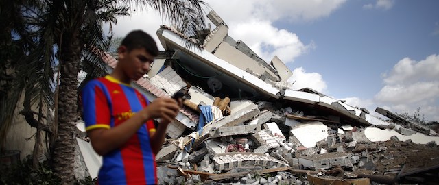 Un ragazzo davanti alle macerie di un edificio a Gaza, distrutto dai bombardamenti israeliani di martedì 15 luglio 2014. (THOMAS COEX/AFP/Getty Images)