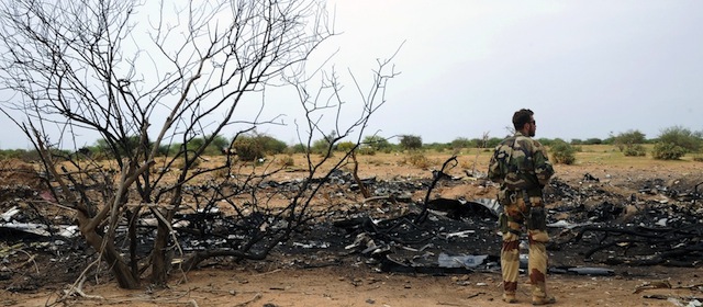 A French soldier looks at the debris at the crash site of the Air Algerie Flight AH 5017 in Mali's Gossi region, west of Gao, on July 26, 2014. UN experts investigating the Air Algerie plane disaster in Mali have recovered the second black box from the doomed plane, a spokesman of UN peacekeepers in the country said on July 26. Officials who had already reached the remote, barren area described a scene of total devastation littered with twisted and burnt fragments of the plane that was carrying 118 on board, including entire families. No one survived the impact and France bore the brunt of the disaster with 54 nationals killed in Thursday's crash of the McDonnell Douglas 83, which had taken off from Ouagadougou in Burkina Faso and was bound for Algiers. AFP PHOTO/ SIA KAMBOU (Photo credit should read SIA KAMBOU/AFP/Getty Images)