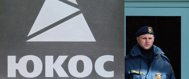 MOSCOW, RUSSIAN FEDERATION: A security guard stands near the logo of Russian oil giant Yukos in Moscow 18 June, 2004. A Moscow court upheld 18 June 2004 the Russian tax ministry's multi-billion dollar claim against Yukos in a ruling likely to push the embattled oil giant toward bankruptcy. AFP PHOTO / DENIS SINYAKOV (Photo credit should read DENIS SINYAKOV/AFP/Getty Images)