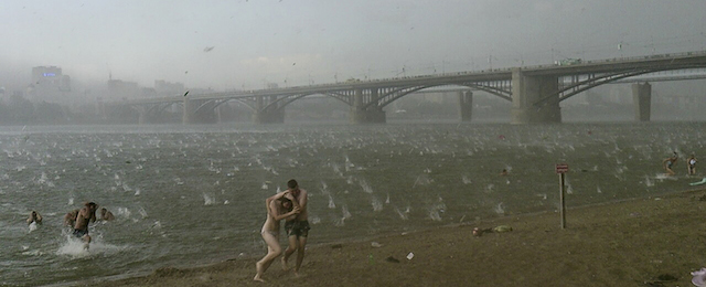 In this photo taken on a smartphone on Saturday, July 12, 2014, people run to shelter from hailstorm on the beach at Ob River, the major river in western Siberia in Novosibirsk, Russia. The Investigative Committee said in a statement published online Monday that two young girls aged three and four had died Saturday in the lakeside town of Bredsk, not far from the large Siberian city of Novosibirsk. The two girls died after sustaining traumatic brain injuries when a tree fell on their tent, where they were taking shelter from the storm along with their families. (AP Photo/Nikita Dudnik)