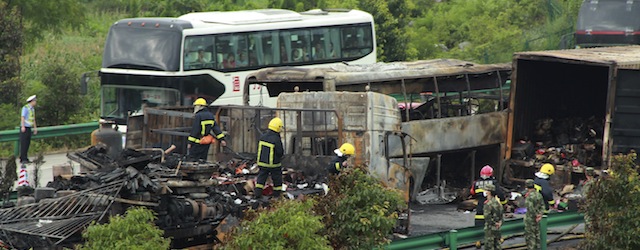 Firefighters and policemen work near a burnt out bus and trucks after an explosion following a traffic accident on the expressway in Longhui county in south China's Hunan province Saturday July, 19, 2014. A truck loaded with flammable liquid collided with a bus on a highway in southern China on Saturday, has killed more than dozens people. (AP Photo) CHINA OUT
