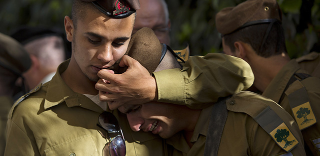 Israeli soldiers hug during the funeral of Staff Sgt. Moshe Melako, 20, at the Mount Herzel military cemetery in Jerusalem, Monday, July 21, 2014. Melako was one of 13 soldiers killed in several separate incidents in Shijaiyah on Sunday, as Israel-Hamas fighting exacted a steep price, killing scores of Palestinians and more than a dozen Israeli soldiers and forcing thousands of terrified Palestinian civilians to flee their devastated Shijaiyah neighborhood, which Israel says is a major source for rocket fire against its civilians. (AP Photo/Sebastian Scheiner)