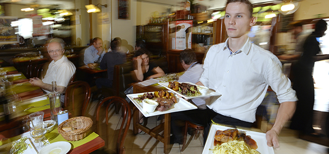 A waiter carries plates of food in the restaurant "Le Mesturet" in Paris on July 15, 2014, on the day a decree relating to the "homemade" designation (fait maison in French) takes effect. A decree relating to the "homemade" designation has passed on July 13 in France, taking effect on July 15. AFP PHOTO/MIGUEL MEDINA