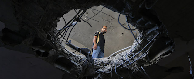 Palestinian Mahmoud Hamad inspects the damage at family house, destroyed by an Israeli strike, in Beit Lahiya, Saturday, July 19, 2014. Palestinian officials reported intensified Israeli airstrikes, shelling and numerous civilian casualties. Gaza Health Ministry spokesman Ashraf al-Kidra said the new round of strikes raised the death toll from the 12-day offensive to more than 330 Palestinians, many of them civilians and nearly a fourth of them under the age of 18.(AP Photo/Lefteris Pitarakis)