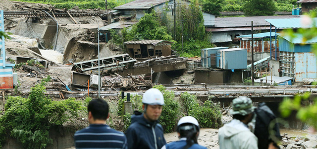 A TV crew works near the Nashizawa river at Nagiso town in Nagano prefecture, central Japan on July 10, 2014 following a mudslide. The landslide was caused by torrential rain on July 9 brought by Typhoon Neoguri. AFP PHOTO / JIJI PRESS JAPAN OUT (Photo credit should read JIJI PRESS/AFP/Getty Images)
