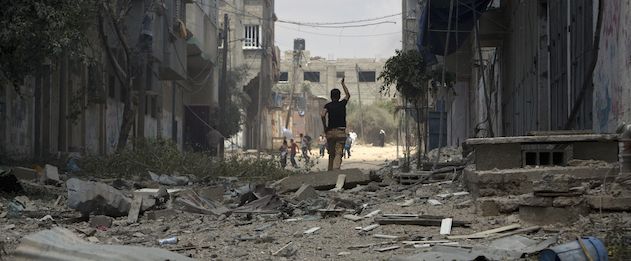 A Palestinian man runs in a street in Gaza's eastern Shejaiya district on July 20, 2014. At least 40 people were killed and nearly 400 wounded in Israeli shelling of Gaza's northeastern Shejaiya district overnight, medics said. AFP PHOTO / MAHMUD HAMS (Photo credit should read MAHMUD HAMS/AFP/Getty Images)