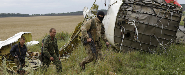 Pro-Russian fighters walk at the site of a crashed Malaysia Airlines passenger plane near the village of Hrabove, Ukraine, eastern Ukraine Friday, July 18, 2014. Rescue workers, policemen and even off-duty coal miners were combing a sprawling area in eastern Ukraine near the Russian border where the Malaysian plane ended up in burning pieces Thursday, killing all aboard. (AP Photo/Dmitry Lovetsky)