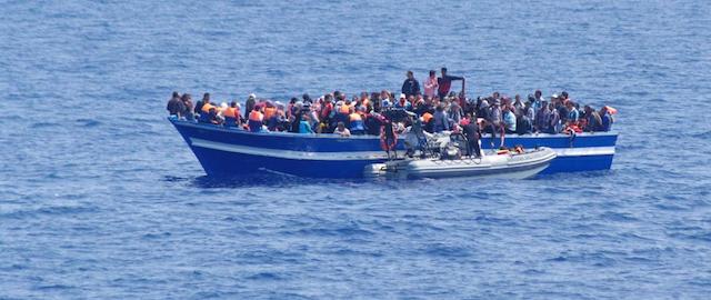 In this photo released by the Italian Navy on Sunday, June 15, 2014, and taken on Saturday, June 14, 2014, a boat filled with migrants receives aid from an Italian Navy motor boat off the coast of Sicily, Italy. The Italian coast guard and navy have rescued more than 300 migrants whose boats ran into trouble in the Mediterranean Sea and recovered the bodies of 10 migrants whose dinghy had overturned. Naval official Salvatore Scimone said 39 survivors on Saturday had grabbed onto the dinghy until rescuers plucked them to safety aboard another boat. He said he feared that an undetermined number of others were missing in the sea north of Libya. In a separate rescue, three Italian ships took aboard 281 migrants who said they were Syrian and whose fishing boat ran into problems. (AP Photo/Italian Navy, ho)